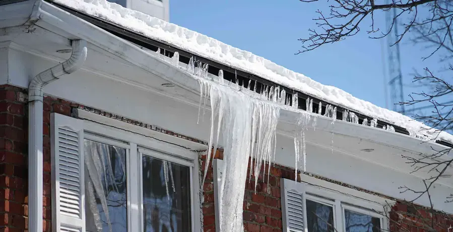 Icicles and an ice dam along the eaves of a brick house